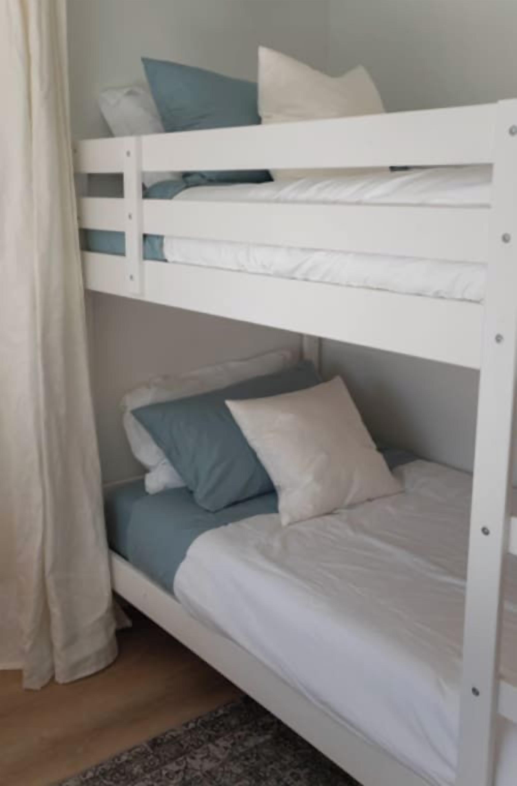 A bunk bed with white bedding and blue pillows.