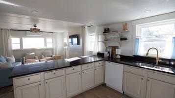 A modern kitchen with white cabinets, a black countertop, and a built-in dishwasher.