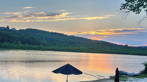 A lakeside view with a row of beach chairs and umbrellas.