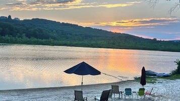 A lakeside view with a row of beach chairs and umbrellas.