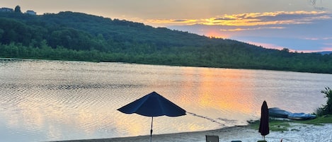 A lakeside view with a row of beach chairs and umbrellas.