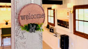 A wooden post with a 'welcome' sign, an anchor decoration, and a small plant.