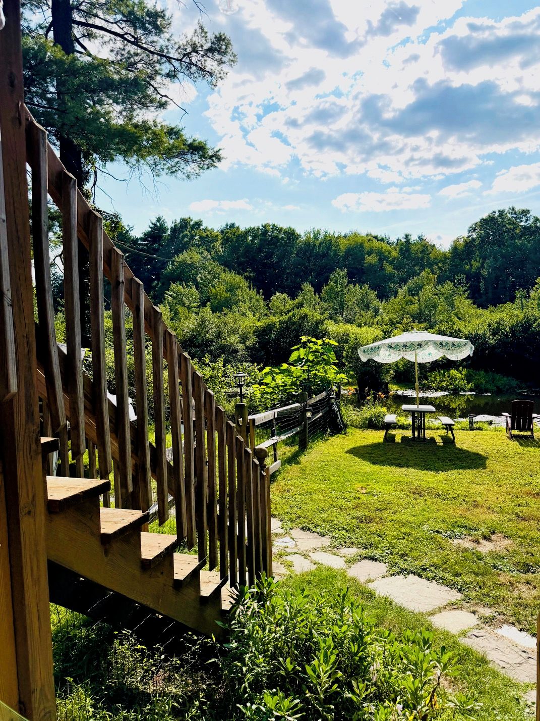 A wooden fence leading to a grassy area with a picnic table and umbrella.