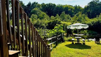 A wooden fence leading to a grassy area with a picnic table and umbrella.