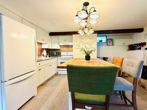 A modern kitchen with white cabinets, a wooden dining table, and a green upholstered chair.