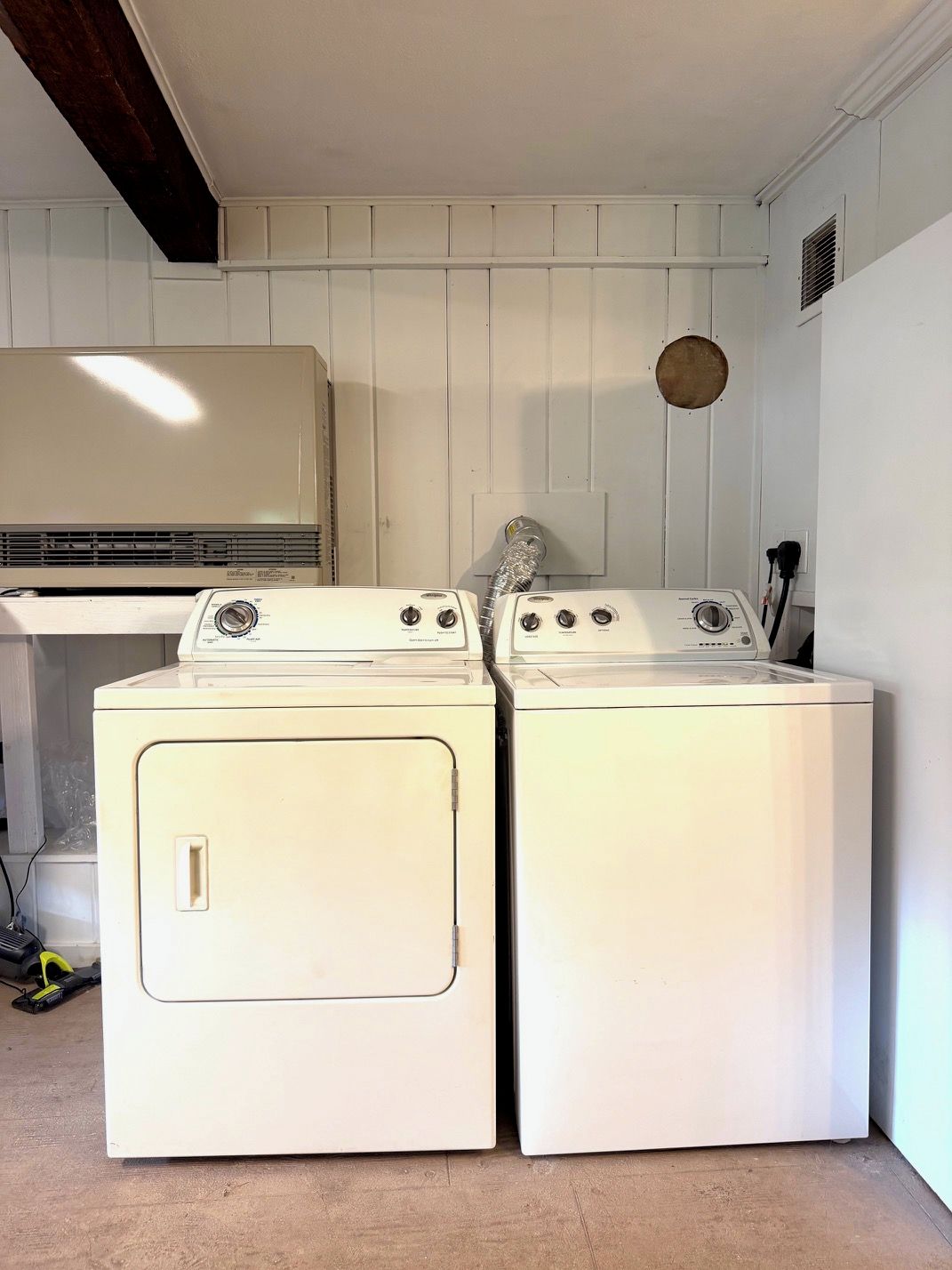 A laundry area with two front-loading washing machines and a wall-mounted dryer.