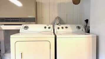 A laundry area with two front-loading washing machines and a wall-mounted dryer.