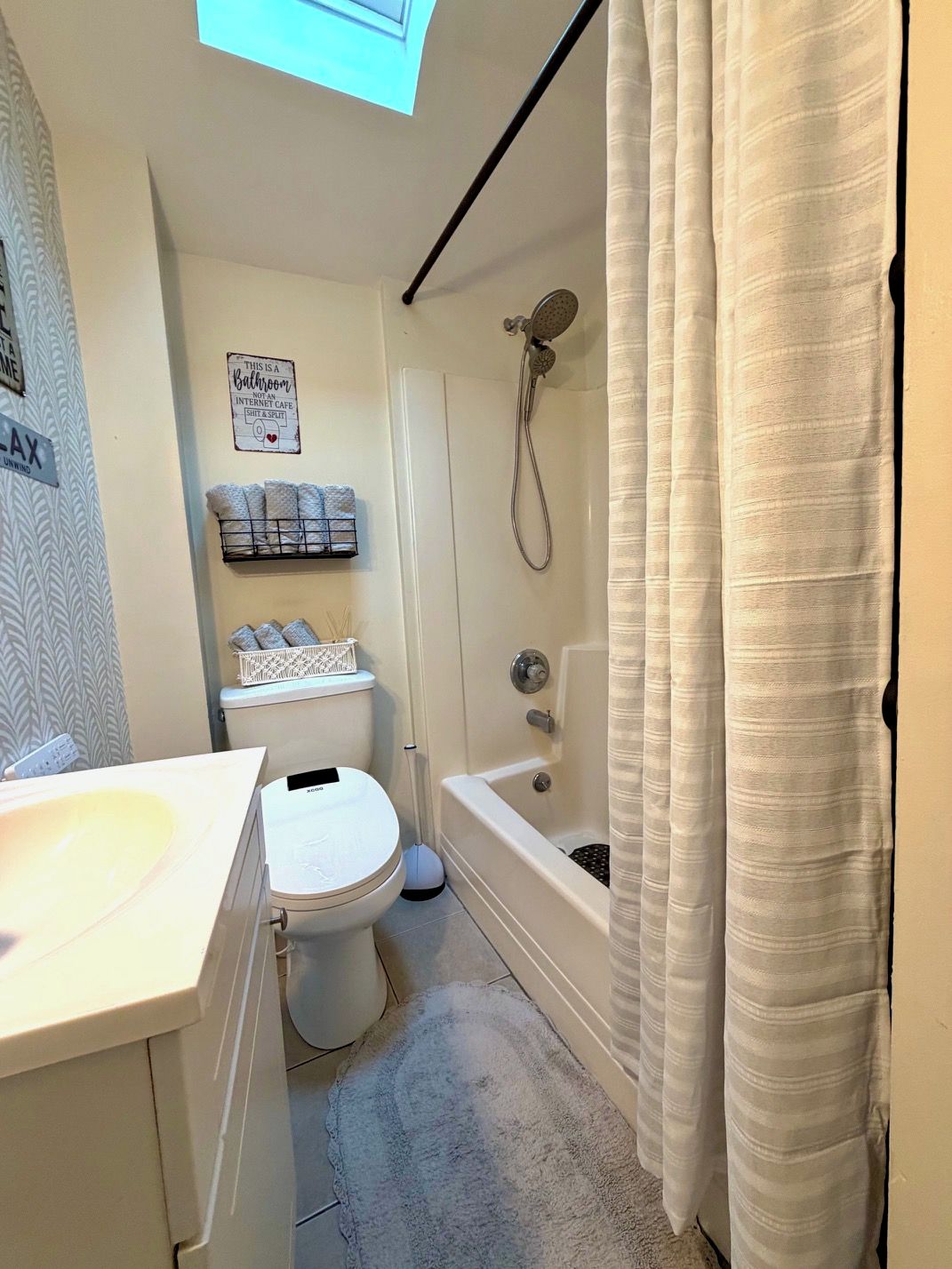 A bathroom with a toilet, sink, shower, and a towel rack.