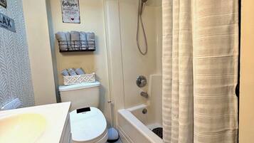 A bathroom with a toilet, sink, shower, and a towel rack.