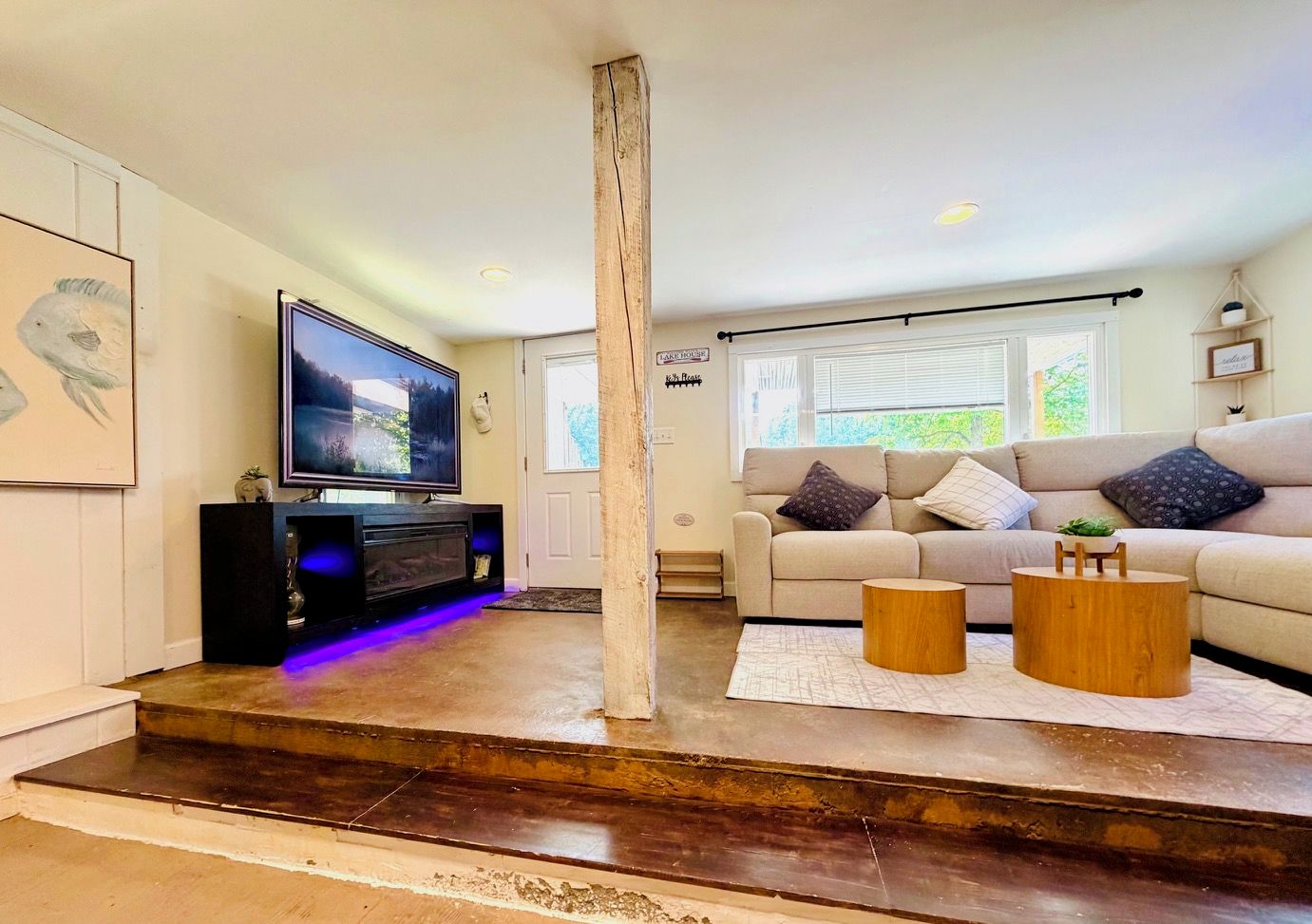 A living room with a flat-screen TV, a sofa, a coffee table, and a staircase.