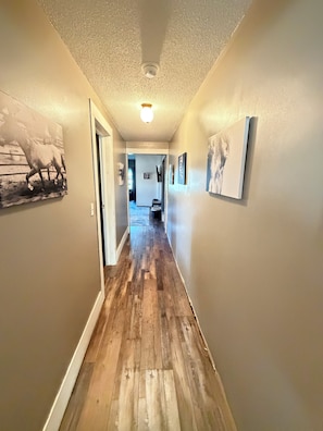 A hallway with wooden flooring, light-colored walls, and artwork.