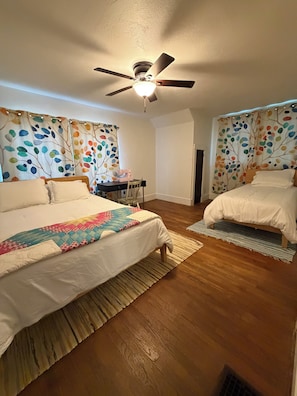 A bedroom with two beds, a ceiling fan, and a sewing machine on a desk.