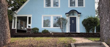 A two-story house with a front porch, a front door, and a small front yard.