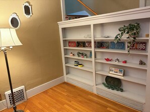A room with a white bookshelf, a lamp, and a vent.