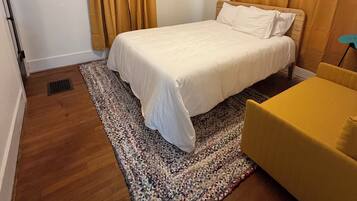 Ein Schlafzimmer mit einem Bett, einem Deckenventilator, einem Teppich und einem gelben Sessel.