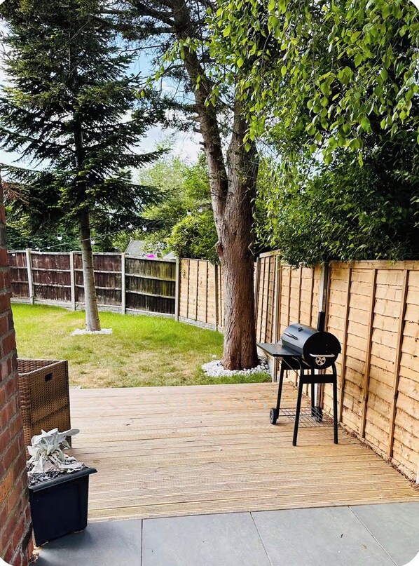 A backyard patio with a barbecue grill, a table, and a basket.
