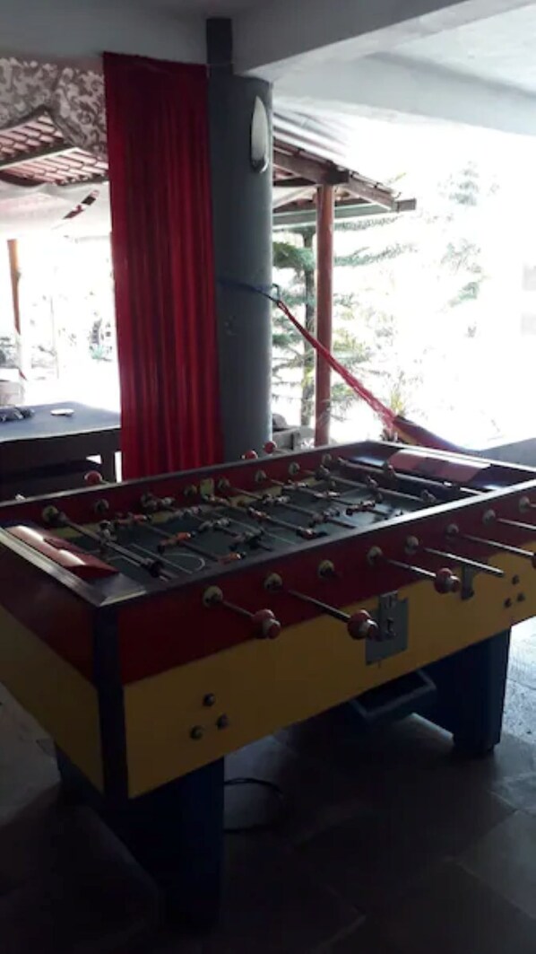 A foosball table in a room with a red curtain and a pillar.