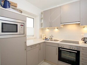 A modern kitchen with a built-in microwave, oven, and sink. - Holiday Apartment in Fohr With 1 Bedroom (Wyk auf Foehr)