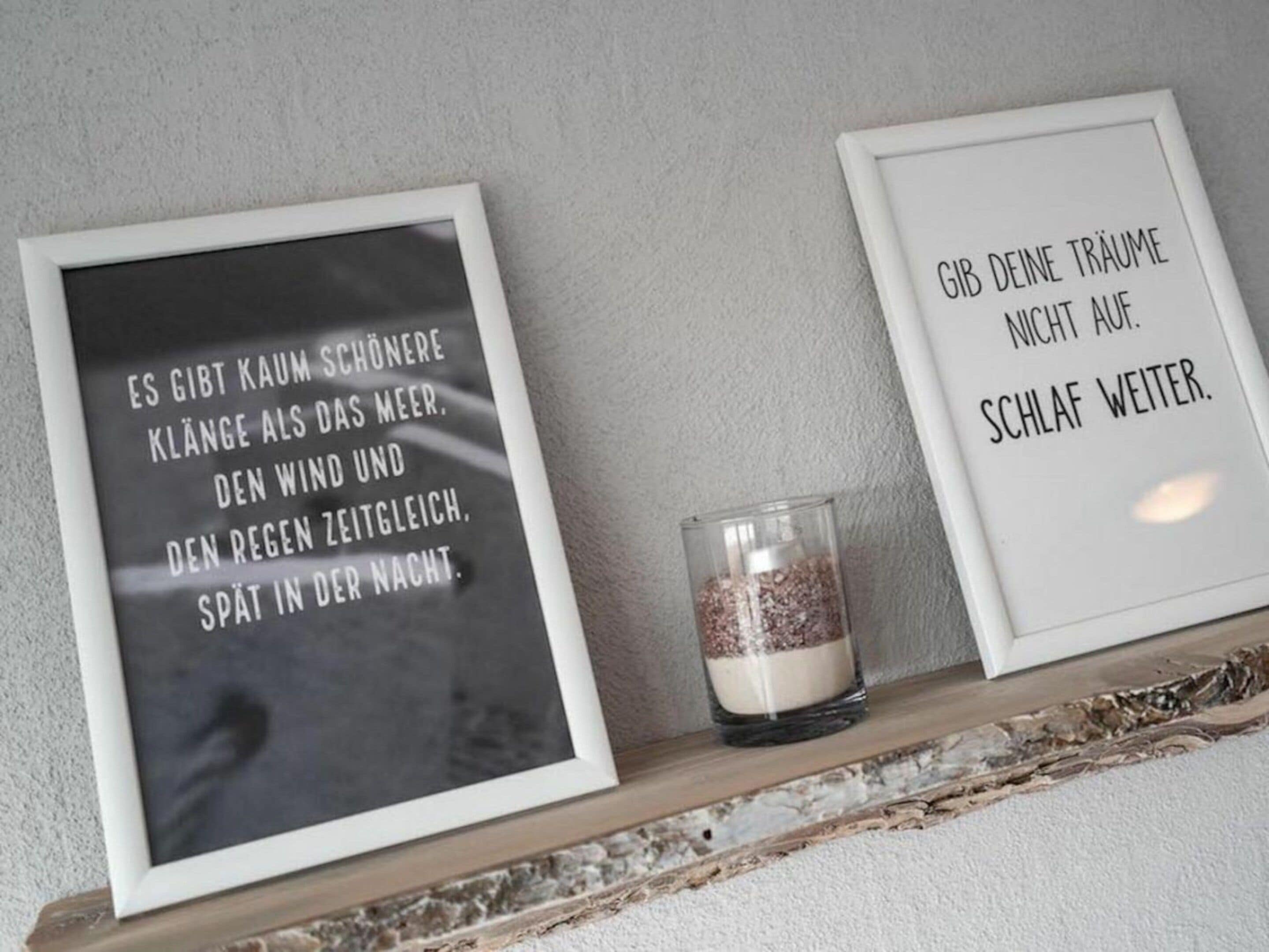 Two framed quotes on a shelf with a candle.