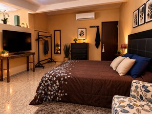 A bedroom with a bed, a TV, a dresser, and a mirror. - Cozy loft-style apartment near downtown Oaxaca (Oaxaca de Juárez)