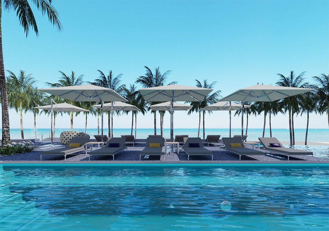 Un espace aménagé au bord de la piscine, avec des chaises longues et des parasols, des palmiers et une vue dégagée sur la plage.
