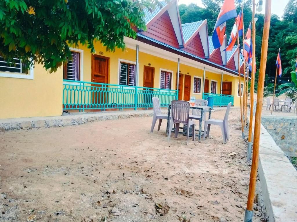Un bâtiment à la façade jaune, doté d’un porche abrité avec des chaises et de plusieurs drapeaux.