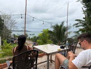 Two people seated at an outdoor table with a view of the sea and mountains. - 7 Makara Bungalow Koh Rong (Koh Rong)