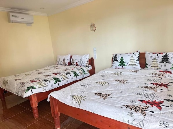 A room with two wooden beds, each with a white bedspread featuring Christmas-themed designs.
