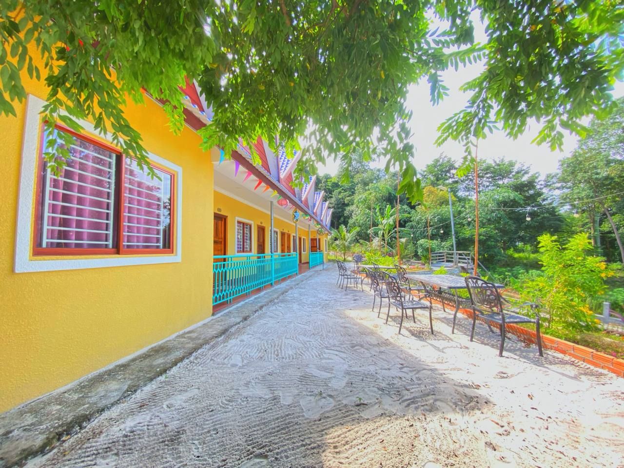 A yellow building with a covered walkway, outdoor seating, and a paved path.