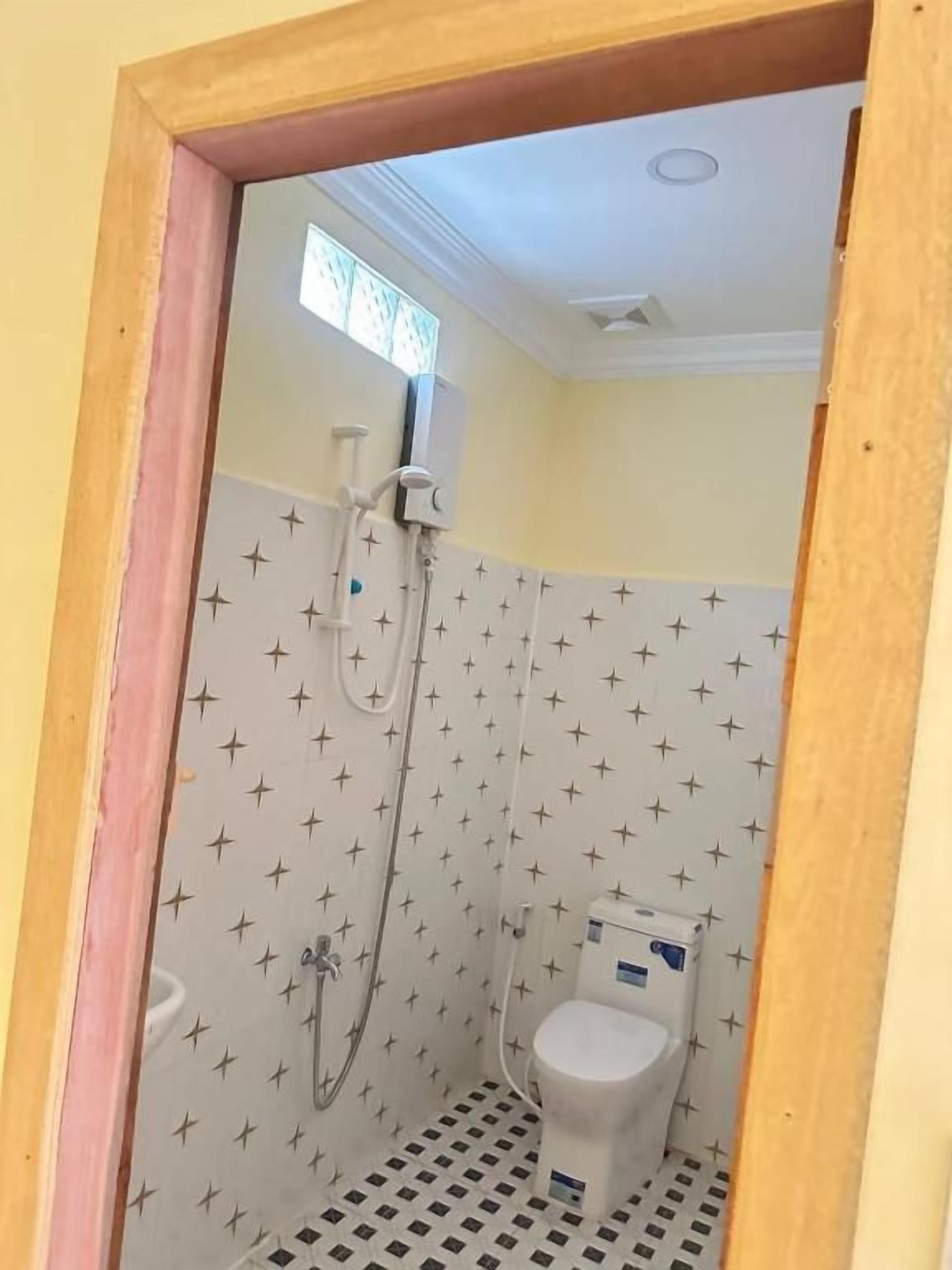 A small bathroom with a shower, toilet, and a window.