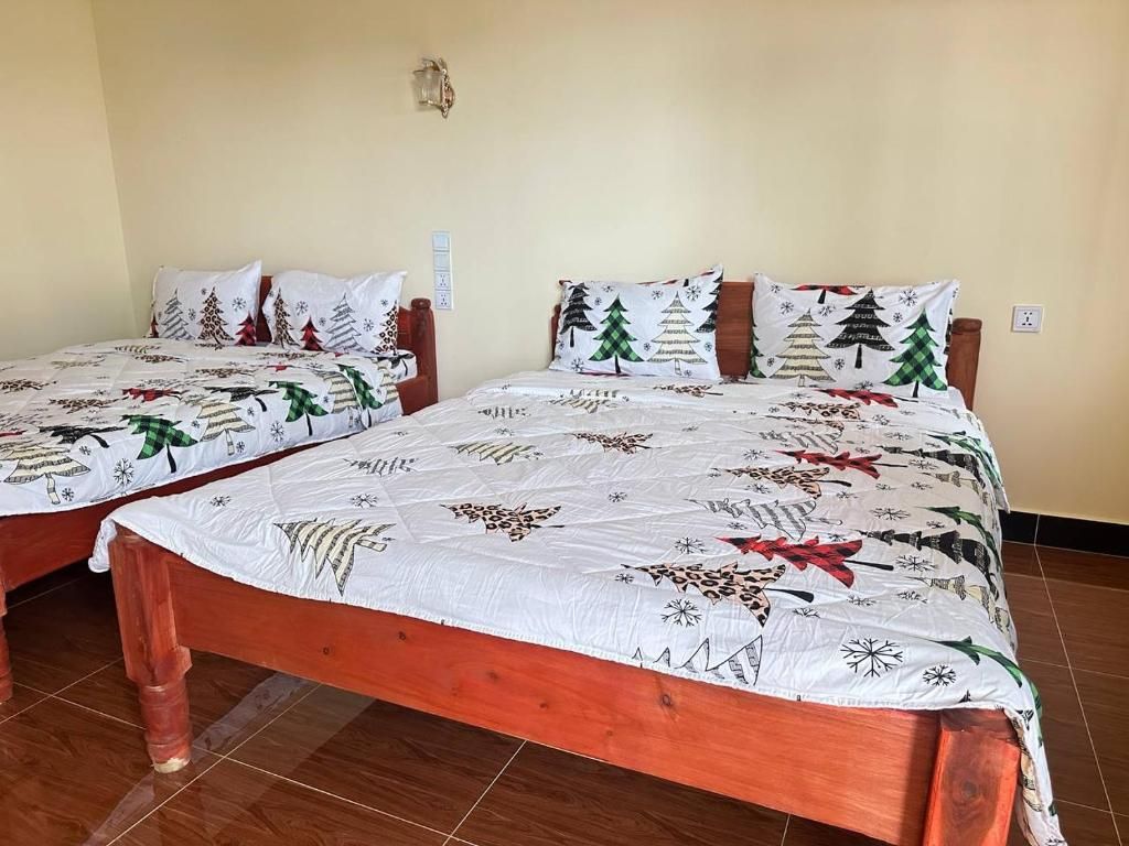 Dos camas de madera con ropa blanca de cama que presenta motivos de árbol de Navidad y copos de nieve.