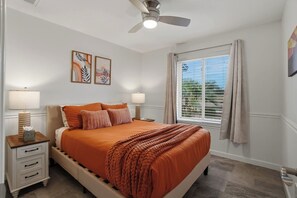A bedroom with a bed, two bedside tables, a ceiling fan, and a window with curtains. - Modern Paradise Retreat Pool & Outdoor Dining (Phoenix)