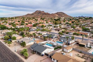 A residential area with houses, a swimming pool, and a mountain in the background. - Modern Paradise Retreat Pool & Outdoor Dining (Phoenix)