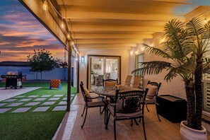 An outdoor patio with a round table and chairs, a grill, and a potted plant. - Modern Paradise Retreat Pool & Outdoor Dining (Phoenix)