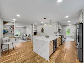 A modern kitchen with a marble island, wooden flooring, and stainless steel appliances. - The Vaughn House-A Peaceful Retreat near Athens GA, by Templin Homes Co (Watkinsville)