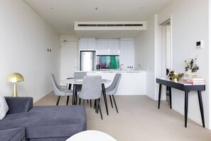 A modern living space with a dining area, a kitchen, and a sofa. - Light Elevated Living near Queen Victoria Market (Melbourne)