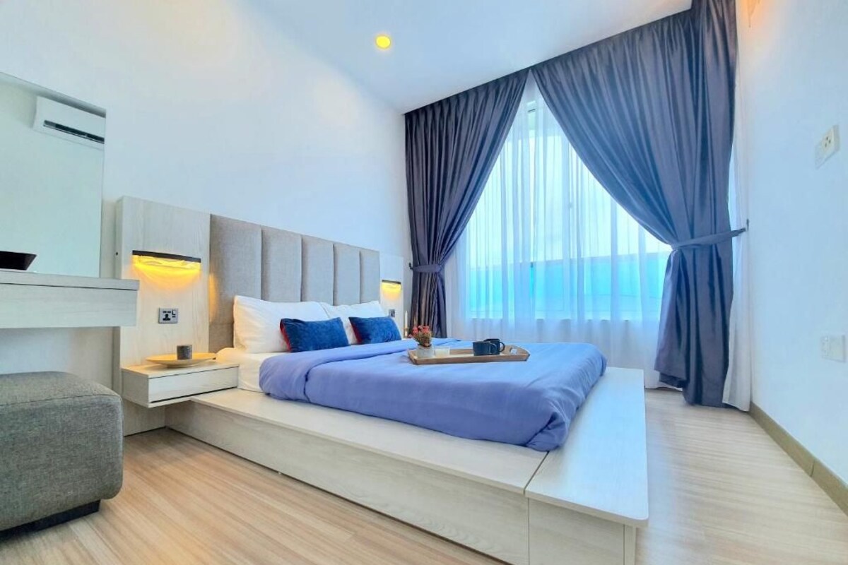 A modern bedroom with a bed, bedside tables, a chair, and a window with curtains.