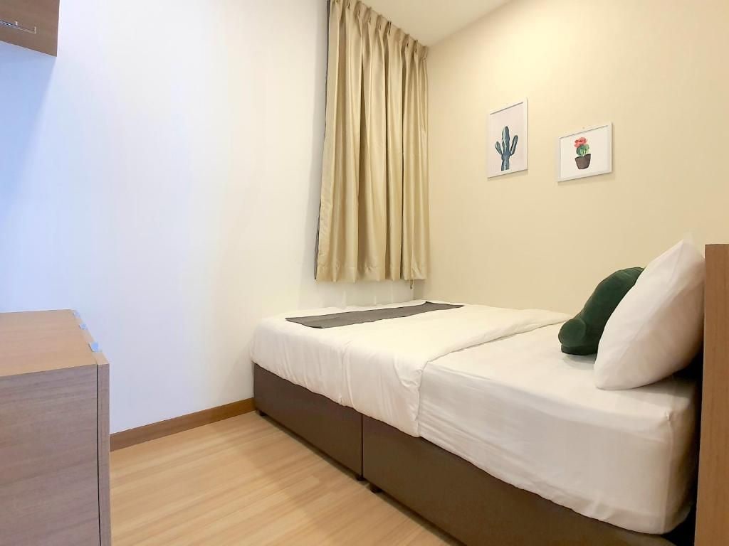 A single bed with a mattress, a bedside table, a wall-mounted shelf, and a window with curtains.