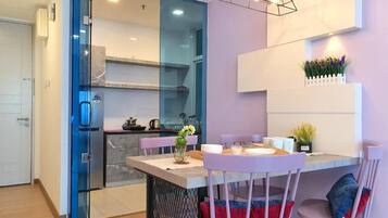 A modern kitchen with a glass partition, a dining area with a table and chairs, and a pendant light fixture.