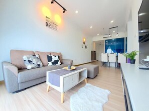 A modern living room with a sofa, a coffee table, and a rug. There is a kitchen area visible in the background. - The Wave Residence (Malacca)