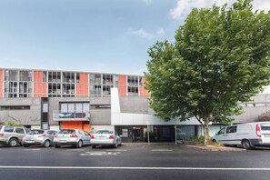 A modern building with a parking lot, a tree, and several cars. - Urban Oasis in the Heart of Richmond Cultural Hub (Richmond)