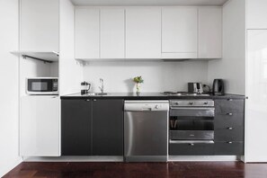A modern kitchen with white cabinets, a stainless steel dishwasher, and a gas stove. - Urban Oasis in the Heart of Richmond Cultural Hub (Richmond)