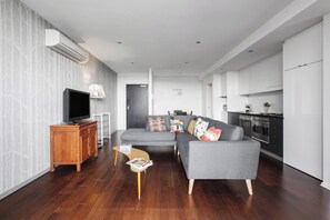 Un salon moderne avec un canapé, un téléviseur et un meuble en bois.