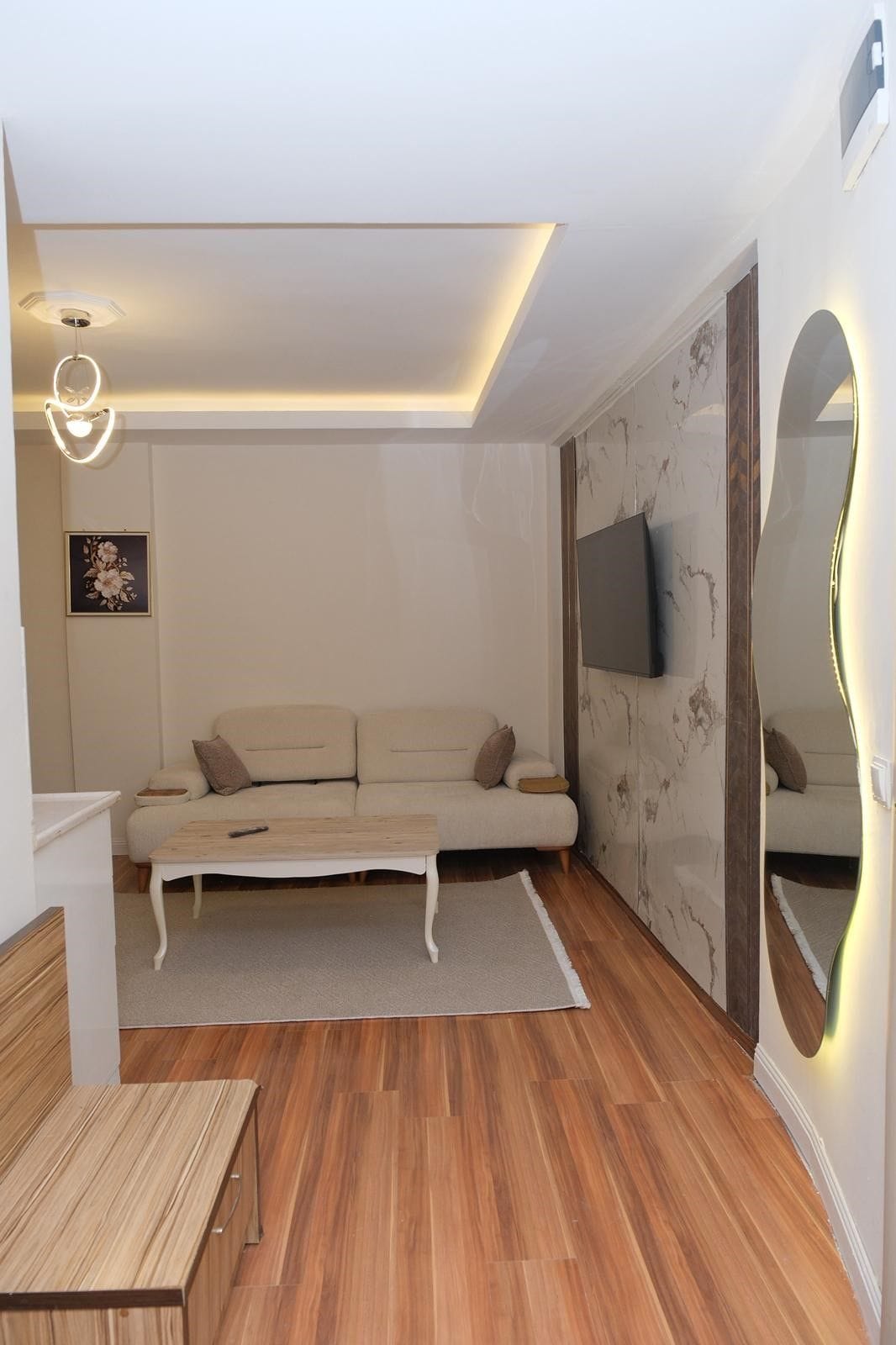 Uma sala de estar moderna com sofá, mesa de centro e TV fixada na parede.