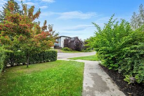 Ein Wohndriveway mit Bürgersteig, Rasen und verschiedenen Bäumen.