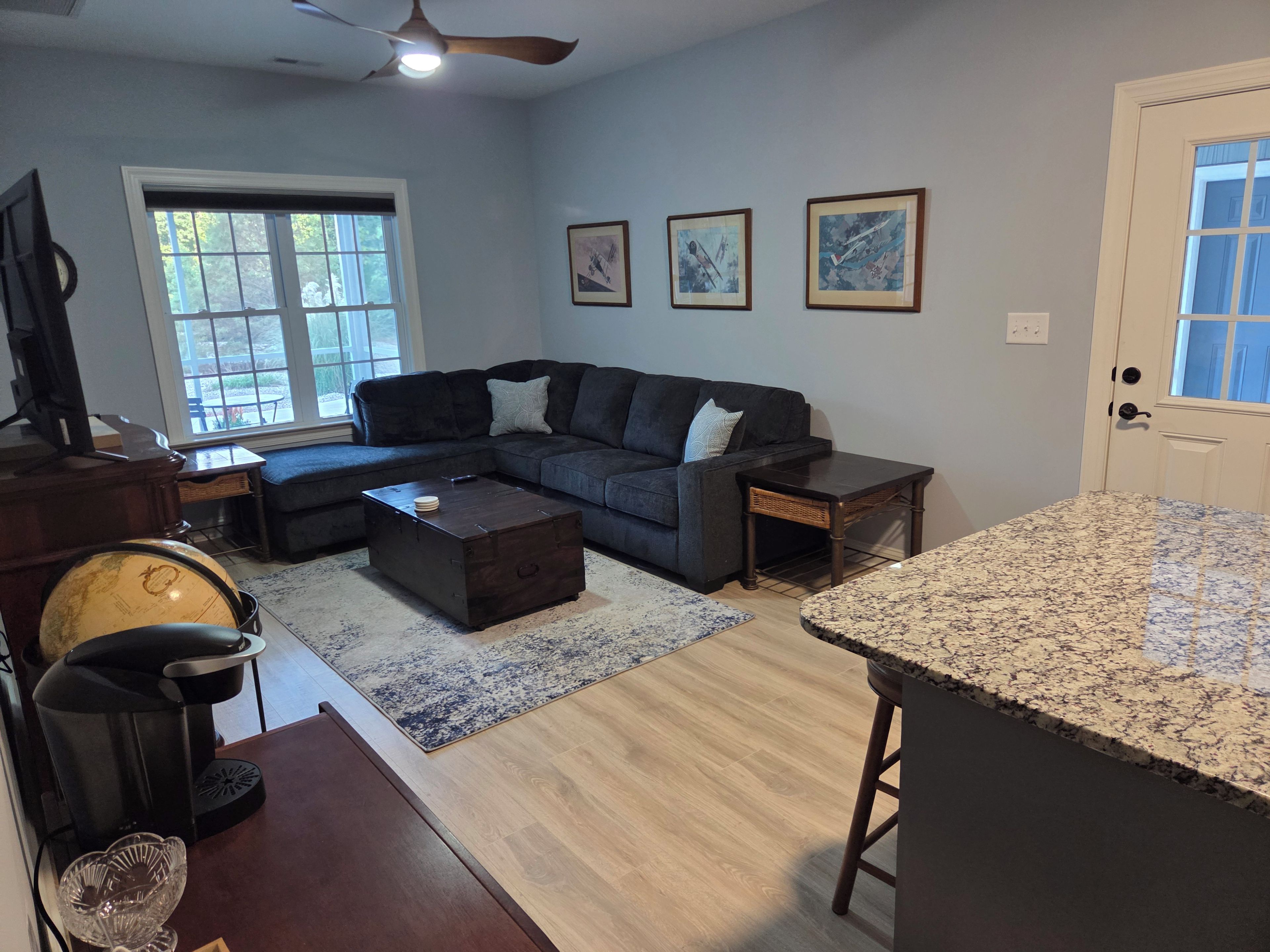 Uma sala de estar com sofá seccional, mesa de centro, bancada de cozinha e mesa de jantar.