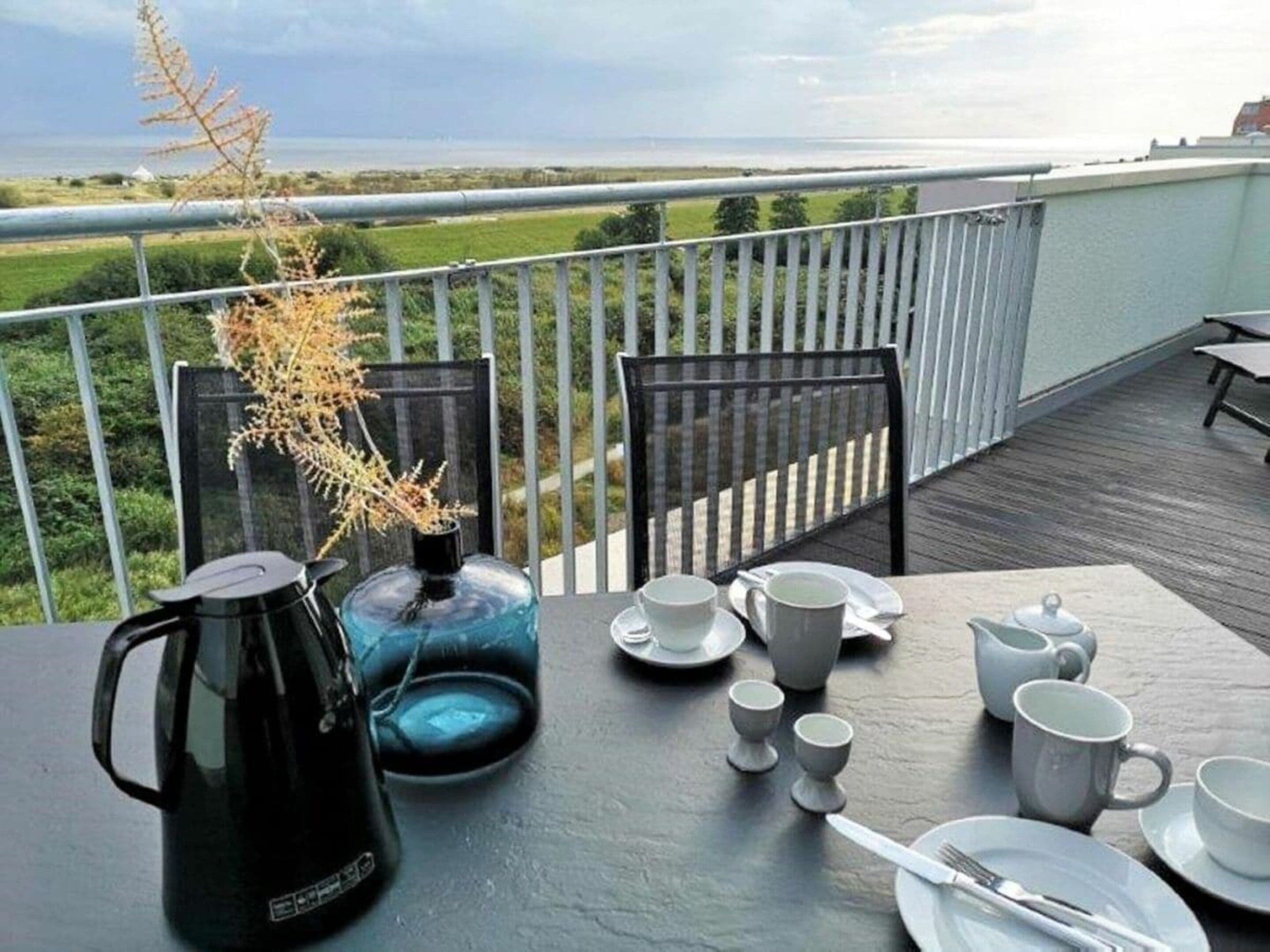 A table set for breakfast on a balcony with a view of the landscape.
