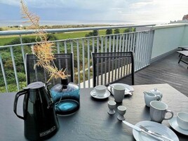 A table set for breakfast on a balcony with a view of the landscape.