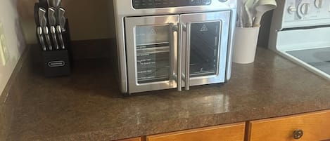 A kitchen with wooden cabinets, a stainless steel oven, and a knife block.