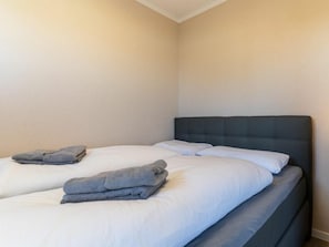 A hotel room with two beds, each with a grey headboard and white bedding. - Utholm 2 Beach Shelter (St. Peter-Ording)